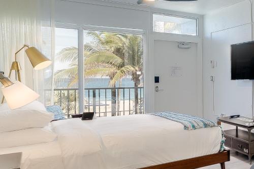 a bedroom with a bed and a window with a palm tree at Plunge Beach Resort in Fort Lauderdale