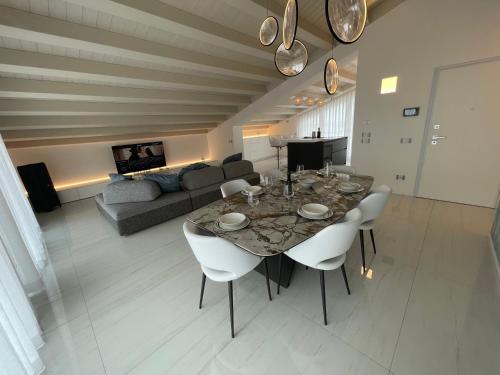a living room with a table and chairs and a couch at Haus Margarete - Attico Infinity Vista Mare con Jacuzzi - Agenzia Cocal in Caorle