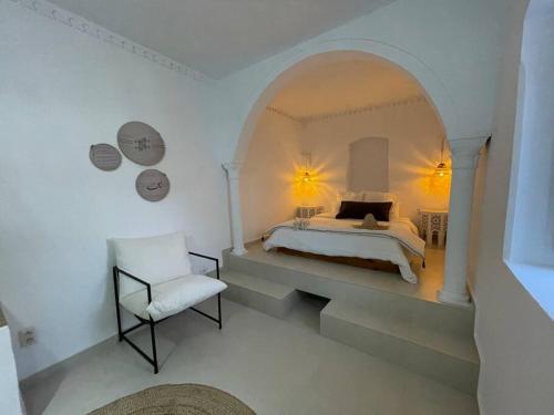 a white bedroom with a bed and a chair at Menzel Al karam, in Temlale