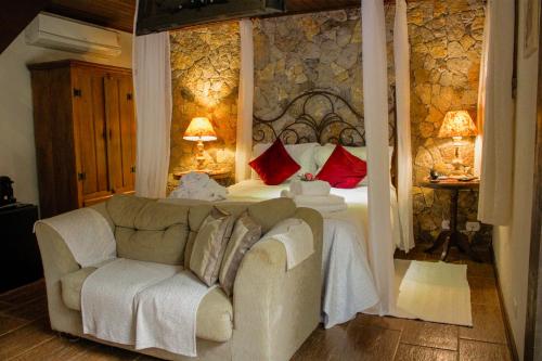 a bedroom with a white bed and a couch at Estalagem Wiesbaden in Monte Verde