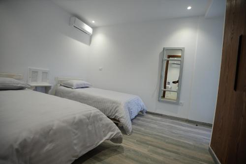 a white room with two beds and a mirror at Le gris Perle in Sfax