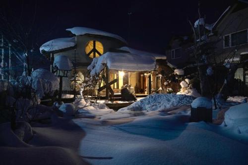a snow covered yard with a house with a clock at Tida House - Vacation STAY 07404v in Koshimizu-shigai
