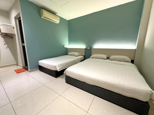 a bedroom with two beds and a blue wall at De UPTOWN Hotel @ Damansara Uptown in Petaling Jaya