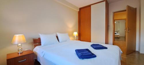 a bedroom with a white bed with two blue towels on it at Golden Delight Central Apartment in Skopje