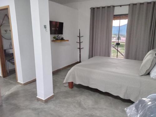 a bedroom with a white bed and a window at Chales Paraíso STL in São Thomé das Letras