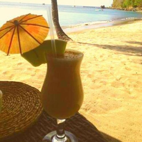 a glass of orange juice sitting on a table on the beach at River Breeze Villa, 5 minutes to beach and town in Soufrière