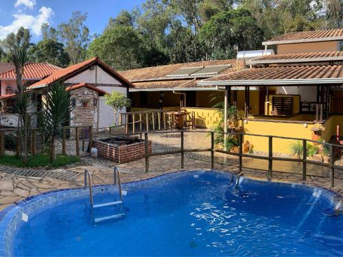 a house with a swimming pool in front of a house at Pousada Casinha Velha in Macacos