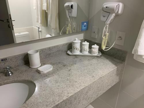 a bathroom counter with a sink and a hair dryer at Flat Manacas Granja Brasil Itaipava in Itaipava