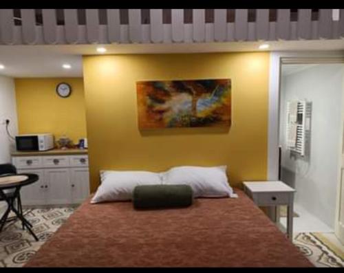 - une chambre avec un grand lit et un mur jaune dans l'établissement Room in Ain Karem - A Maltese Traditional Townhouse, à Mosta