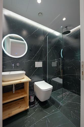a bathroom with a toilet and a sink and a mirror at Cako Rooms Saranda in Sarandë