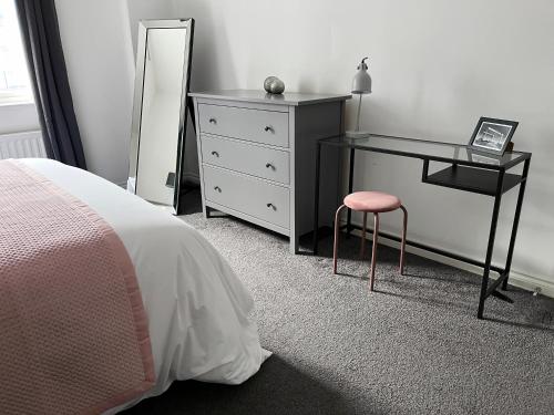 een slaapkamer met een bureau en een dressoir met een roze kruk bij Academy Street Apartments in Belfast