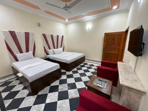 Habitación con 2 camas y suelo a cuadros. en Decent Lodge Guest House F-11 en Islamabad