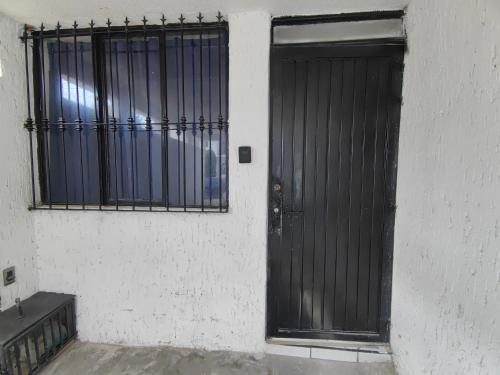 a black door on a white wall with two windows at Monoambiente in San Luis Potosí