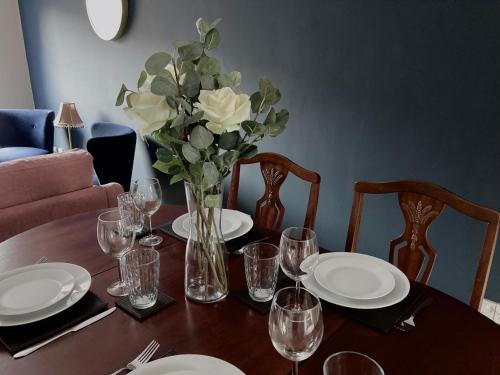 una mesa con platos y vasos y un jarrón de flores en Erin Way Apartments, en Belfast