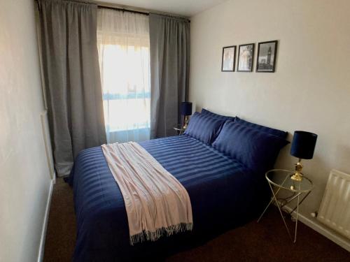 - une chambre avec un lit bleu et une fenêtre dans l'établissement Erin Way Apartments, à Belfast