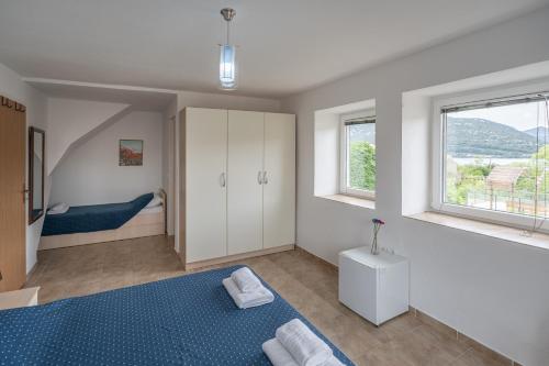 a bedroom with a blue bed and two windows at ENA Kuća za odmor in Ston