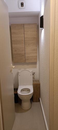 Elle comprend une petite salle de bains pourvue de toilettes et de placards en bois. dans l'établissement CAP AU CAP - T3 avec Clim WIFI Vue piscine proximité plage Richelieu, au Cap d'Agde