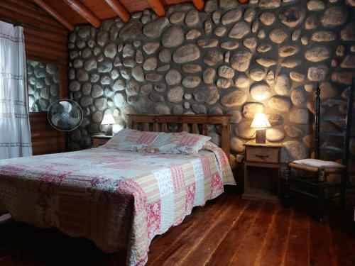 um quarto com uma cama e uma parede de troncos em Azul em Arroyo de Los Patos