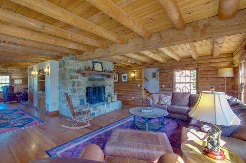 a living room with a stone fireplace in a log cabin at Cozy Log Cabin Getaway with Fire Pit and 3 Acres! in Ruckersville