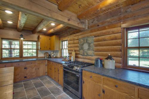 a kitchen with wooden cabinets and a stove top oven at Cozy Log Cabin Getaway with Fire Pit and 3 Acres! in Ruckersville