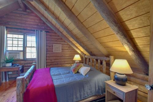 Cozy Log Cabin Getaway with Fire Pit and 3 Acres! في Ruckersville: غرفة نوم مع سرير في كابينة خشب