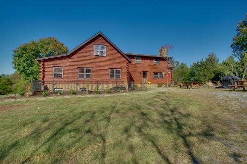 a large red barn with a picnic table in front of it at Cozy Log Cabin Getaway with Fire Pit and 3 Acres! in Ruckersville