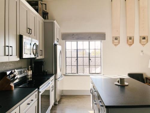 a kitchen with white cabinets and a large window at Neyland View Condo - Heart of Downtown Knoxville in Knoxville