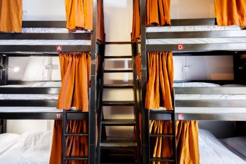 a room with three bunk beds and orange curtains at Palmers Lodge Swiss Cottage in London