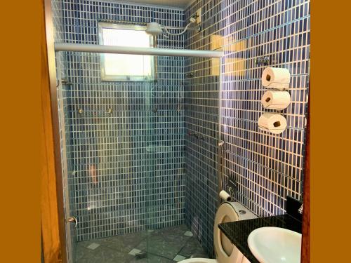 uma casa de banho em azulejos azuis com um lavatório e um WC em Pousada Casinha Velha em Macacos