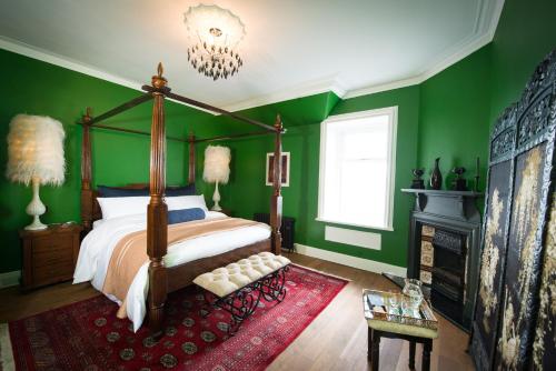 a bedroom with green walls and a bed and a chandelier at Ardrhu House Fort William - Superior Room in Fort William