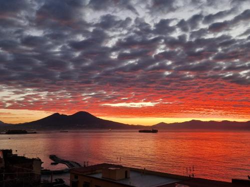 un tramonto su un corpo d'acqua con montagne di La Stella dei Venti B&B a Napoli
