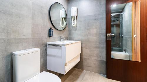 a bathroom with a toilet and a sink and a mirror at Albergaria Quim Barreiros in Vila Praia de Âncora