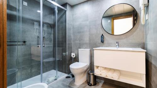 a bathroom with a toilet and a shower and a mirror at Albergaria Quim Barreiros in Vila Praia de Âncora