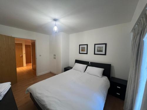 a bedroom with a large white bed and a hallway at Modern 1 Bed Flat in Colindale, London in Colindale