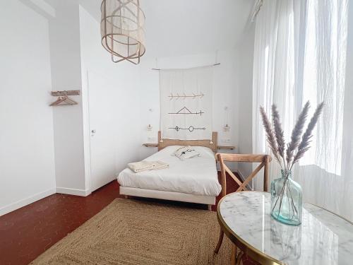 Cette chambre blanche dispose d'une table et d'un lit. dans l'établissement - Maison ŪMA - Mer et centre -, à Marseille