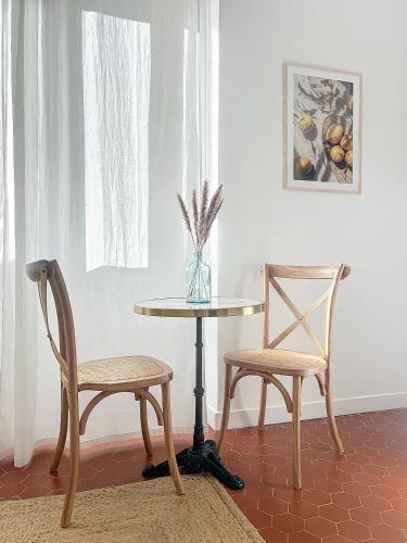 une table, deux chaises et une table avec un vase dans l'établissement - Maison ŪMA - Mer et centre -, à Marseille