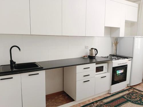 a kitchen with white cabinets and a black counter top at 12 Microragion Apartments in Aktobe