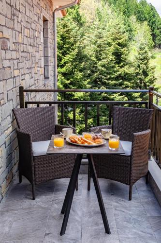 a table with food and orange juice on a balcony at FLOARA DI MUNTE Forest Luxury Suites in Metsovo