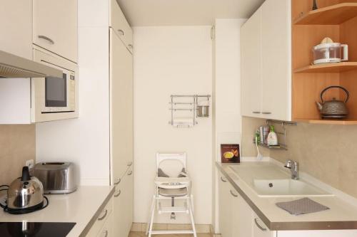 une cuisine blanche avec un évier et un comptoir dans l'établissement Apt Opéra-Richelieu/Heart of Paris, à Paris