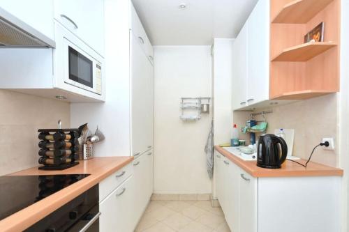 une petite cuisine avec des armoires blanches et un micro-ondes dans l'établissement Apt Opéra-Richelieu/Heart of Paris, à Paris