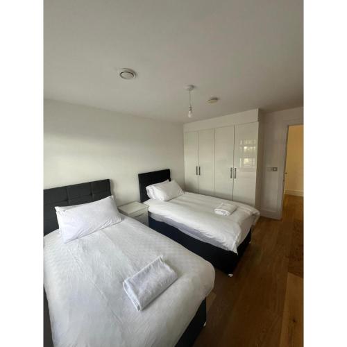two beds in a room with white sheets at Spacious 1 Bedroom Flat in Kilburn Park F55 in London