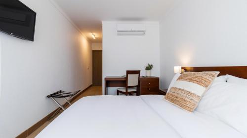 a bedroom with a white bed and a desk at Albergaria Quim Barreiros in Vila Praia de Âncora