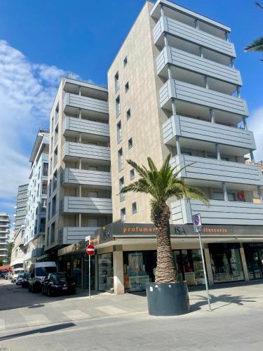 eine Palme vor einem hohen Gebäude in der Unterkunft Appartamento Lignano Sabbiadoro Centro in Lignano Sabbiadoro
