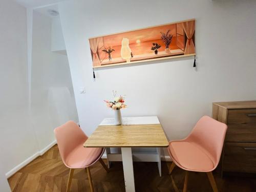 une table avec deux chaises roses et un vase avec des fleurs dans l'établissement Dream Dwell Paris - Apart super 150m de Centre Pompidou, à Paris