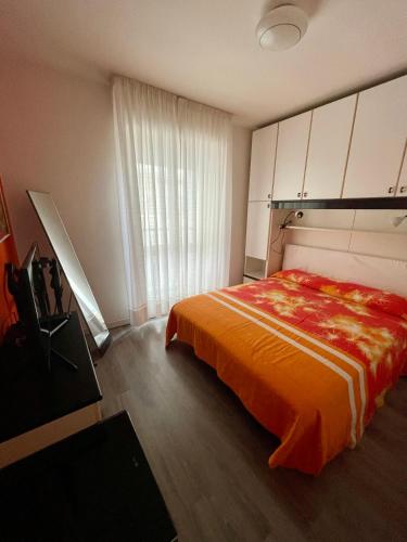 a bedroom with a bed with an orange blanket at Appartamento Lignano Sabbiadoro Centro in Lignano Sabbiadoro