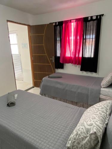 a bedroom with two beds and a window with red curtains at Casa em Piranhas Aconchego in Piranhas