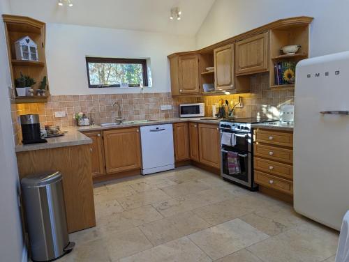 a kitchen with wooden cabinets and white appliances at Little Chilsbury in Potterne