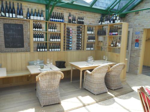 un restaurante con 2 mesas, sillas y botellas de vino en Tannine et Cuisine en Jabbeke