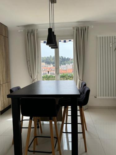 une table à manger noire avec des chaises et une fenêtre dans l'établissement Dernier étage, vue panoramique Colline du Château!, à Nice
