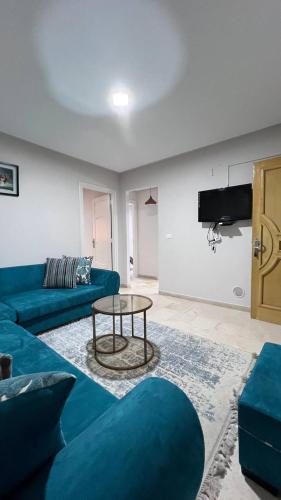 een woonkamer met een blauwe bank en een tafel bij Chez-moi in Sfax